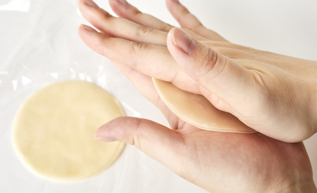 餃子の皮を両手で軽く挟んで温めている写真