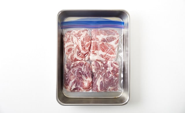 冷凍用保存袋に入れた豚肉をバットにのせている写真