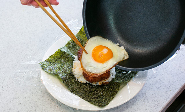 『極上ヒレかつ』の上に目玉焼きを重ねている様子