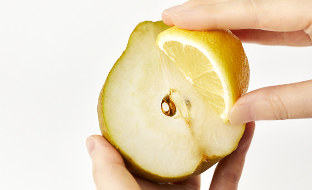 半分にカットしたラフランスにレモン汁を塗る写真
