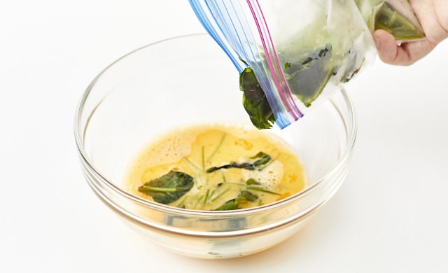 卵液に三つ葉を加えている写真