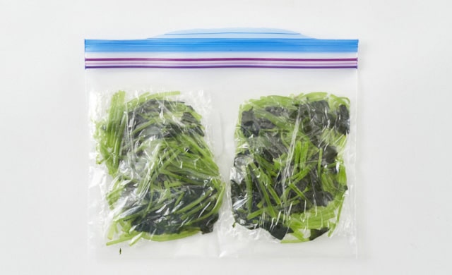 ゆでた三つ葉を冷凍用保存袋に入れている写真