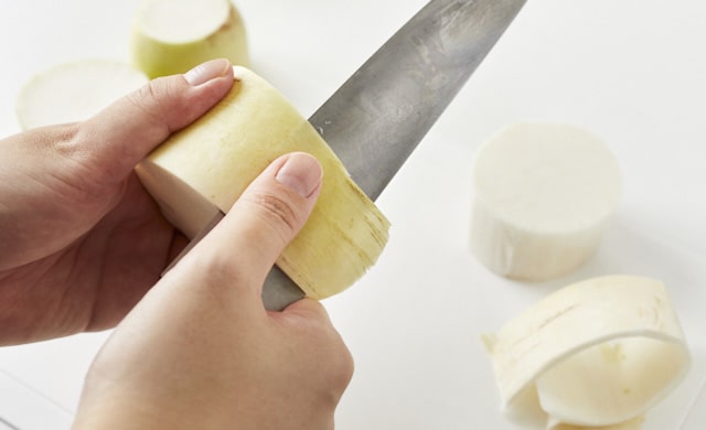 輪切りにした大根の皮をむいている写真