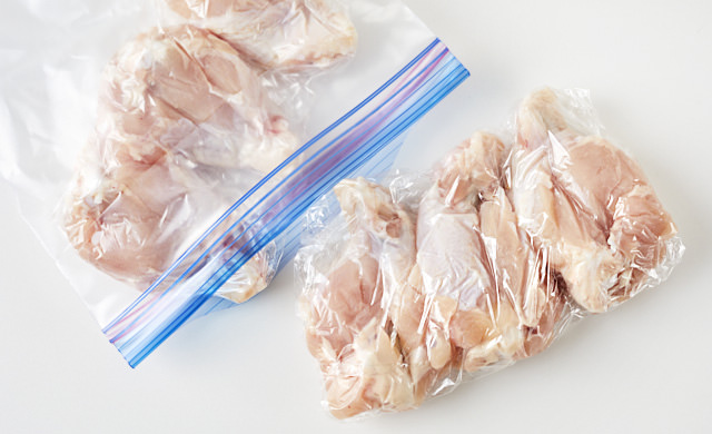 鶏手羽元3本をラップに包んで冷凍用保存袋に入れようとする写真
