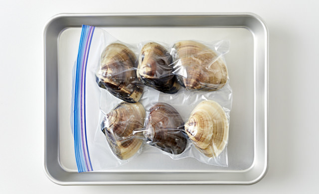 冷凍用保存袋に入れ、金属製のバットにのせたはまぐりの写真