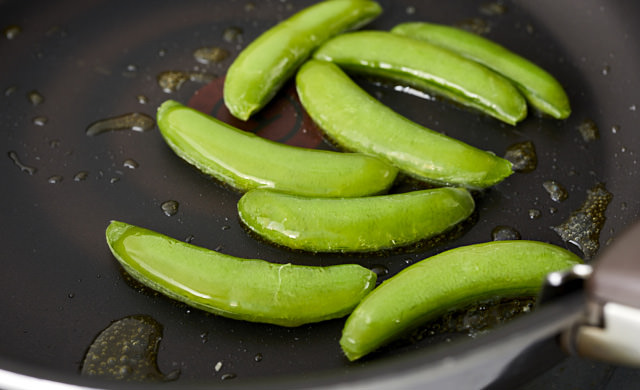 スナップエンドウを油で炒めている写真