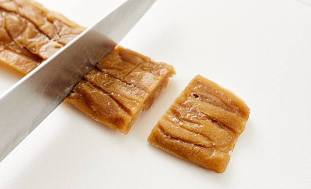 凍ったかんぴょうの甘辛煮をカットしている写真