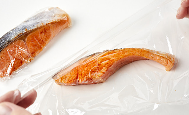 焼き魚をラップで包んでいる写真