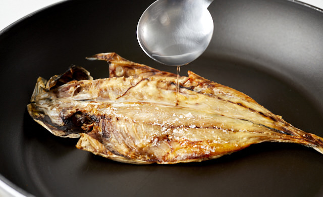 凍ったアジの開きの焼き魚に水を振りかけている写真