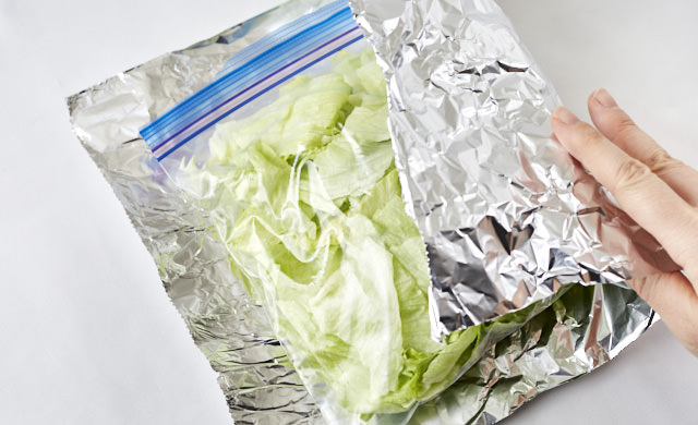 冷凍用保存袋に入ったレタスをアルミホイルで包んでいる写真