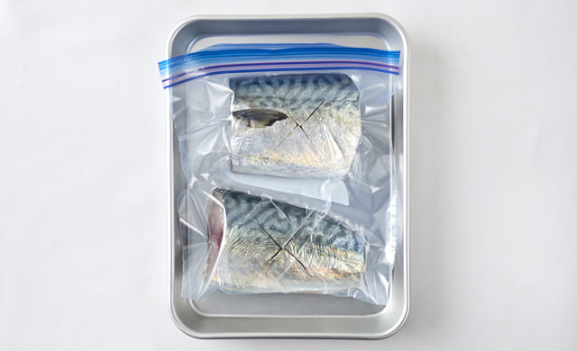 冷凍用保存袋に入った鯖をバットに並べている写真