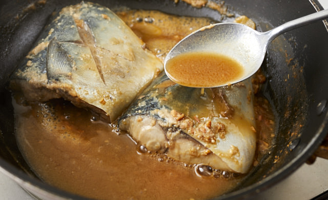 鯖に煮汁をかけている写真