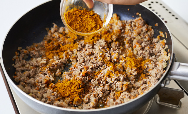 カレー粉を加えて炒めている写真