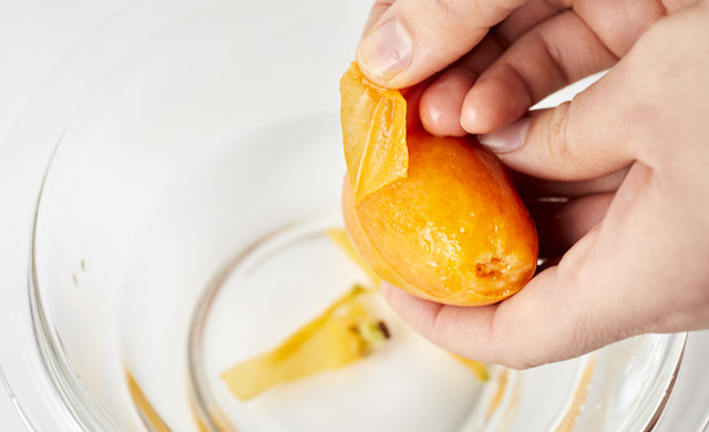 冷凍したびわの皮をむいている写真