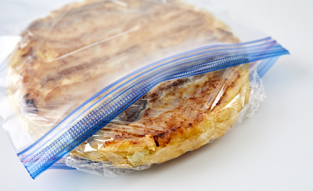 ラップで包んだお好み焼きを冷凍用保存袋に入れている写真