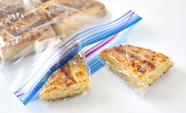 ラップで包んだお好み焼きを冷凍用保存袋に入れている写真