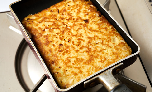 お好み焼きを卵焼き器で焼いている写真