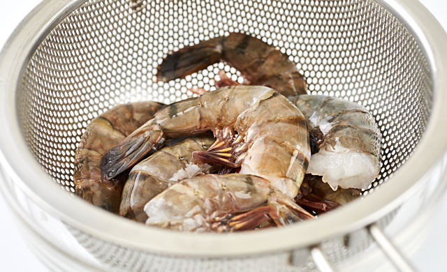ザルに上げた解凍した冷凍殻付きエビの写真