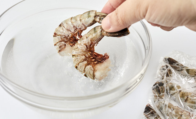 冷凍殻付きエビを重曹を溶かした水で解凍する写真