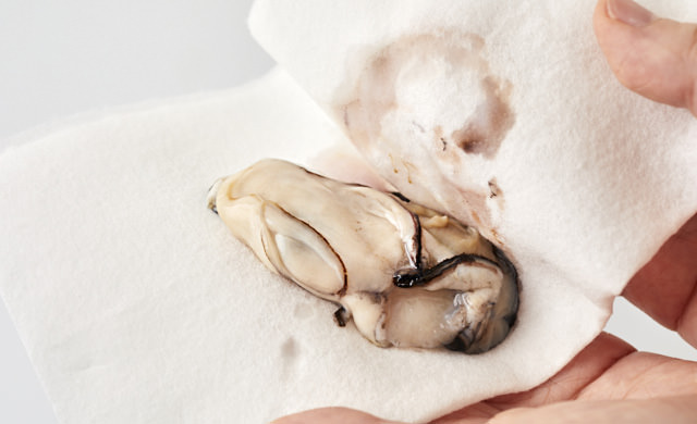 牡蠣の水気を拭いている写真