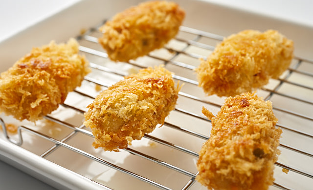 揚げフライを網付きバットに取り出した写真