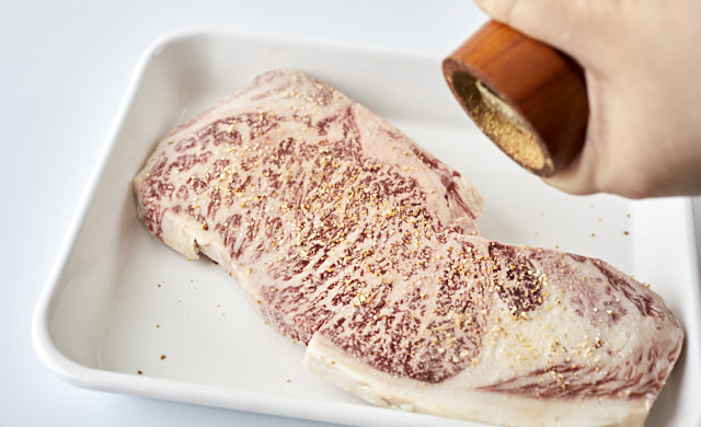 ステーキにこしょうを振っている写真