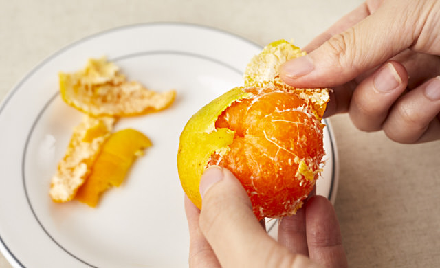 冷凍みかんの皮をむいている写真
