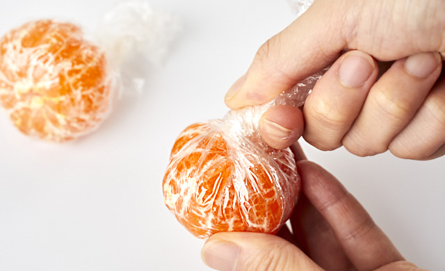 皮をむいたみかんをラップで包んでいる写真