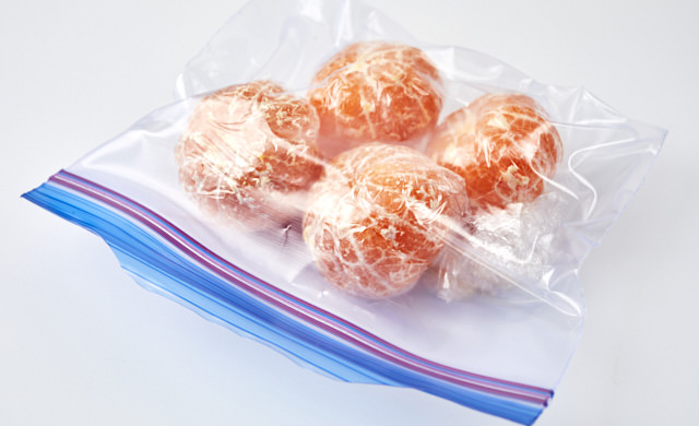 皮をむいたみかんを保存袋に入れている写真