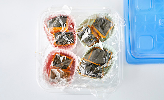 シリコンカップに入れたかぼちゃの煮物を保存容器に入れている写真