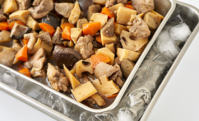 バットに広げた筑前煮を氷水に当てている写真