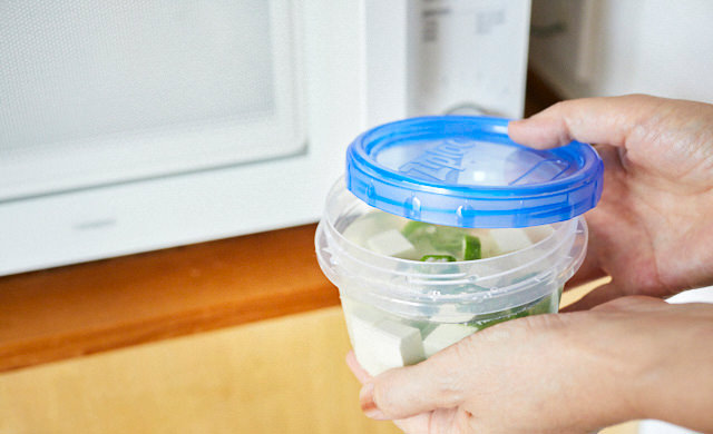 ふたをずらしてかぶせた耐熱容器を電子レンジに入れている様子