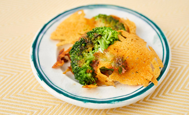 ブロッコリーのチーズ焼きを皿にのせている写真