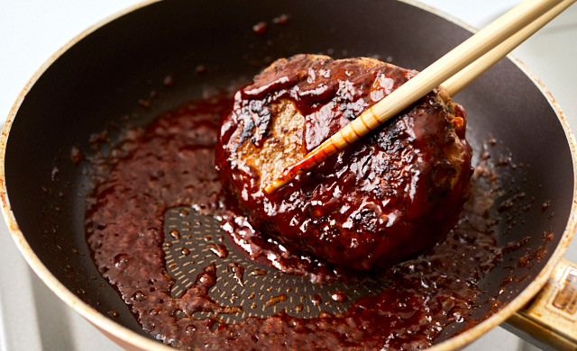 ハンバーグをソースと絡めている写真