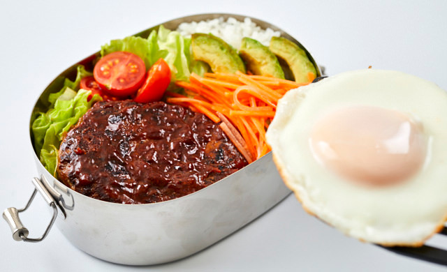 ロコモコ弁当に目玉焼きをのせている写真