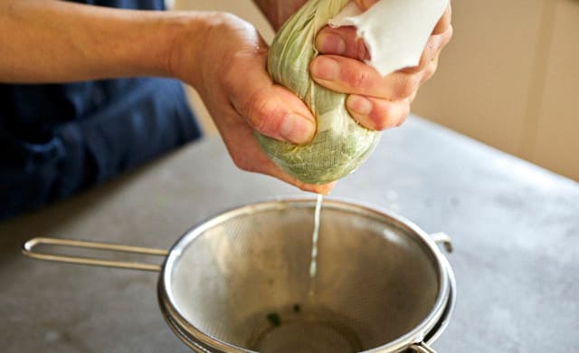 解凍したほうれん草の水気を絞っているシーン