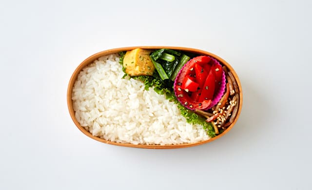 お弁当箱に小さなおかずを詰めた写真