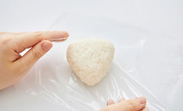 おにぎりをラップで包んでいる写真