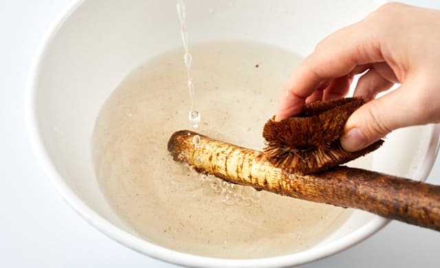 ごぼうの皮をたわしでこすっている写真