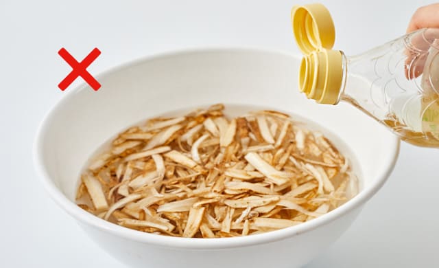 ごぼうをつけている水に酢を加えようとしている写真