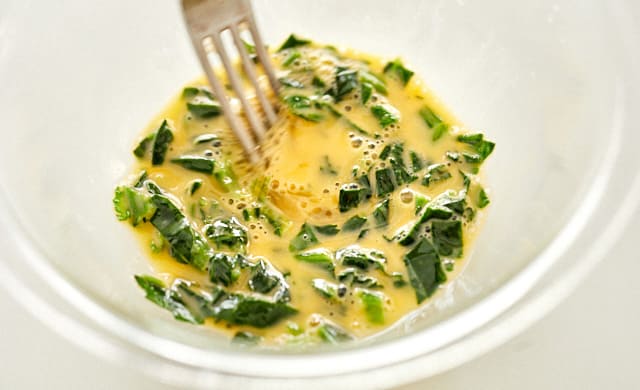 溶き卵にほうれん草を加えている写真