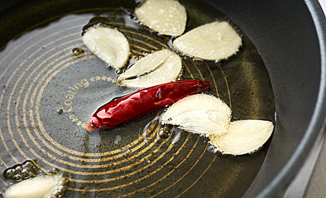 フライパンにオリーブオイル・にんにく・赤唐辛子を入れている写真