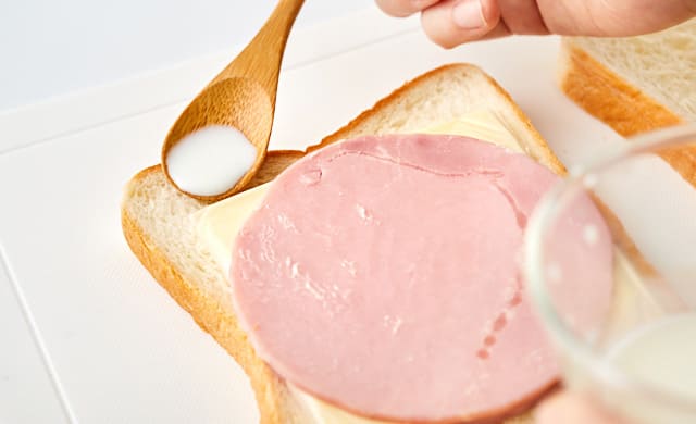 サンドイッチのふちに牛乳を塗っている写真