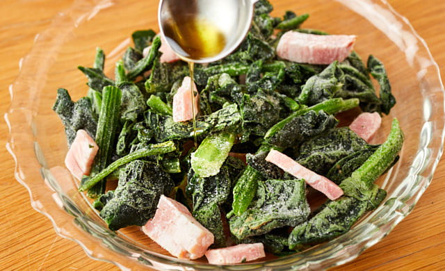 『ベーコンほうれん草』 にオリーブオイルを回しかけている様子