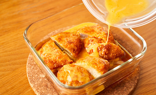 ヒレかつに溶き卵を回しかけている様子