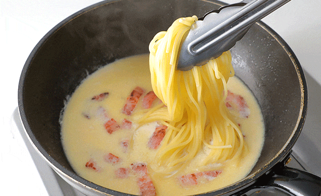ソースにパスタを加えている写真