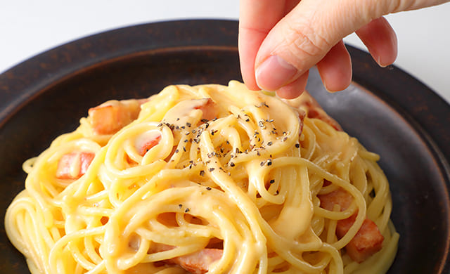 カルボナーラにこしょうをふっている写真