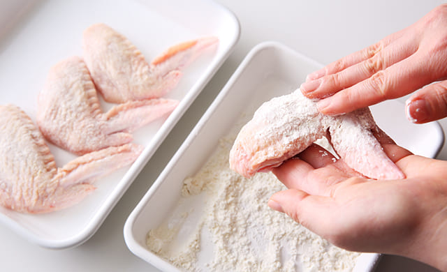 手羽先に小麦粉をまぶしている写真