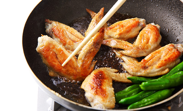 手羽先を調味料と煮絡めている写真