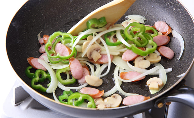 ピーマンとマッシュルームを加えて炒めている写真